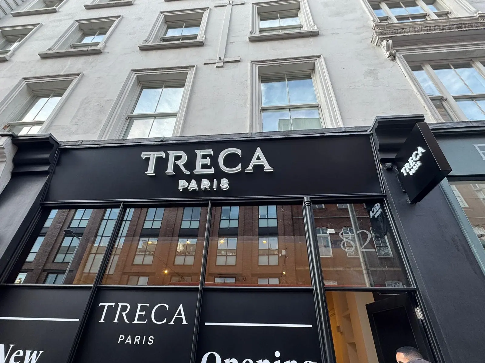 Elegant black storefront signage for Treca Paris, creating a bold brand presence