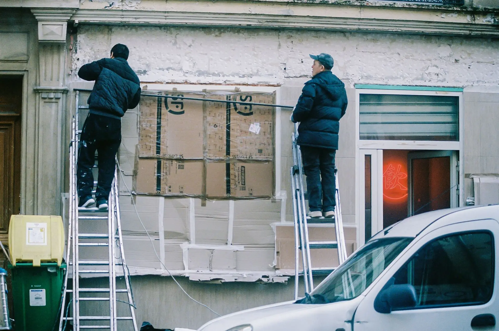 Workers installing a large business sign on a storefront.