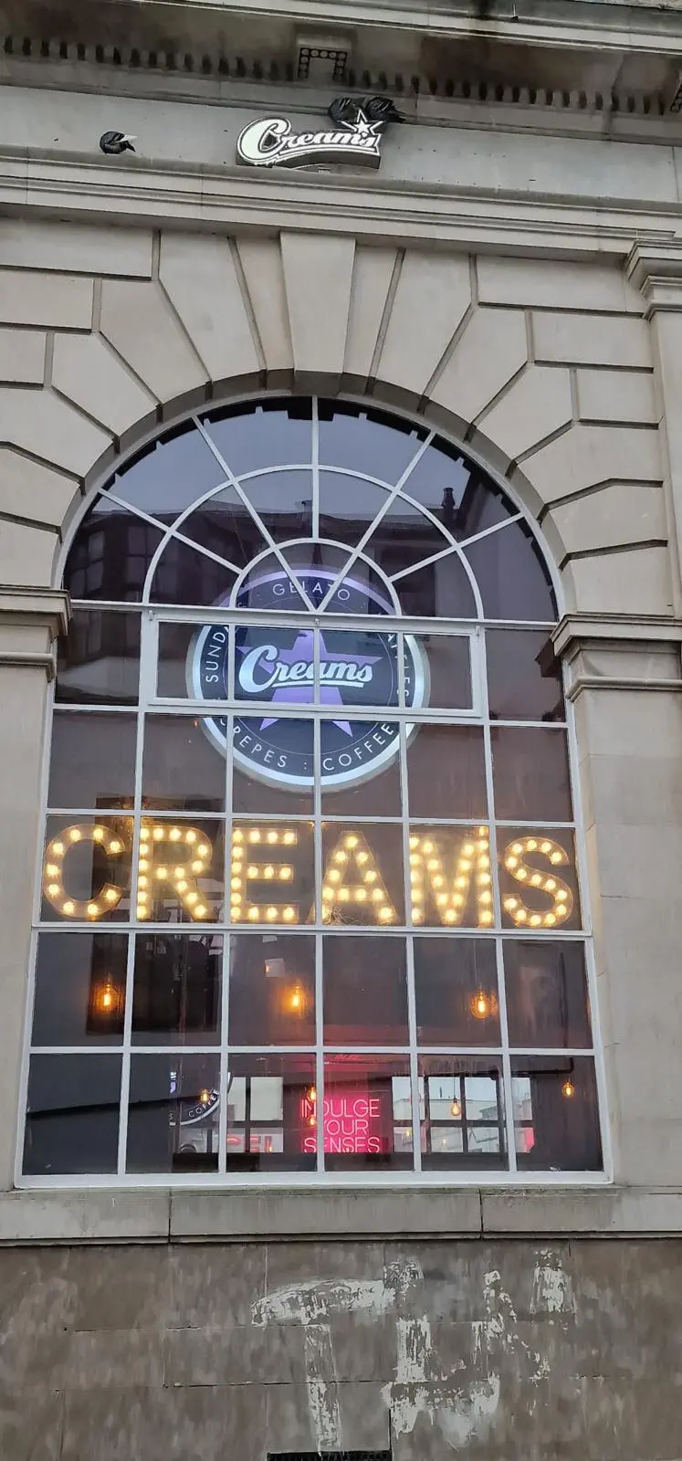 Illuminated signage for Creams Cafe featuring warm LED lights for high visibility