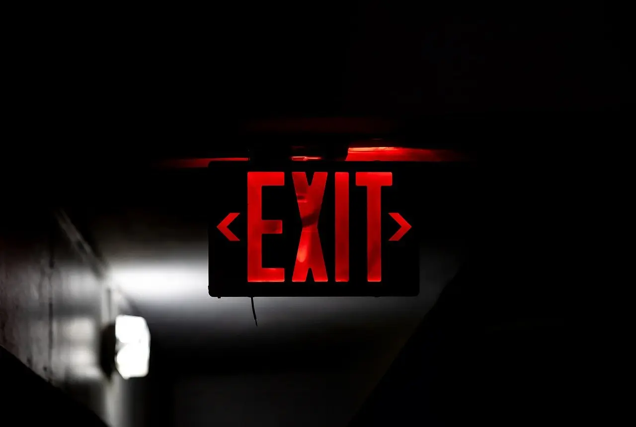 Red illuminated exit sign for emergency wayfinding in an office.