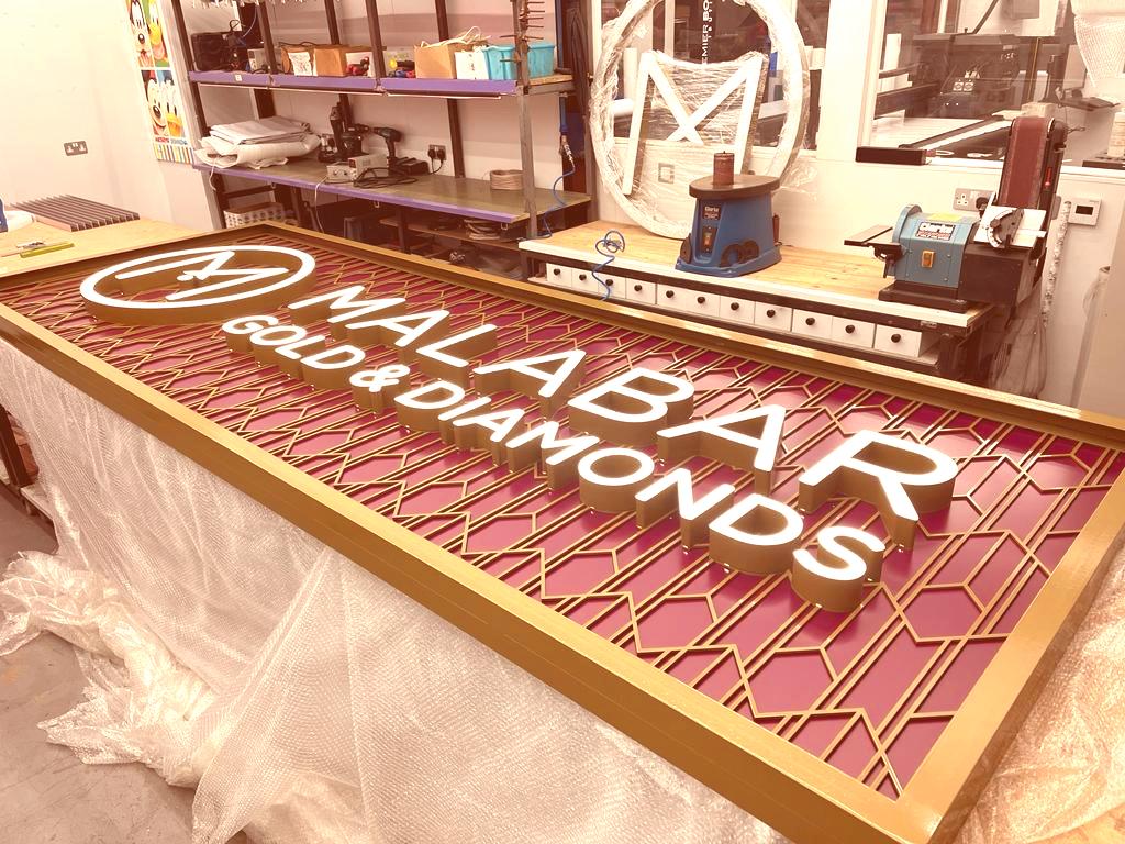 Malabar Gold & Diamonds illuminated signage under fabrication in a workshop.