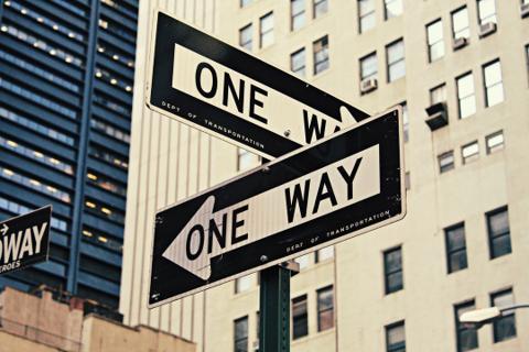 Black and white "One Way" directional signage in an urban environment for navigation